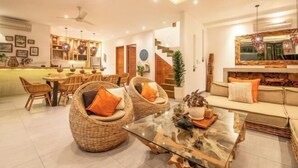 A modern interior with wicker furniture, a glass coffee table, and a staircase leading to an upper level. - Villa Chili in Dalung (Bali)