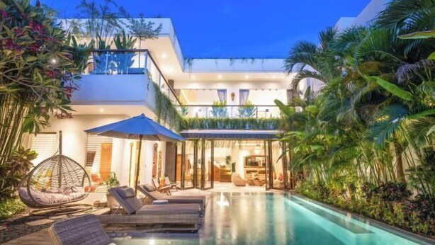 A modern pool area with lounge chairs and a hanging chair, surrounded by lush tropical plants. - Villa Chili in Dalung (Bali)