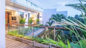 A modern building with a glass facade, a wooden deck, and lush greenery. - Villa Chili in Dalung (Bali)