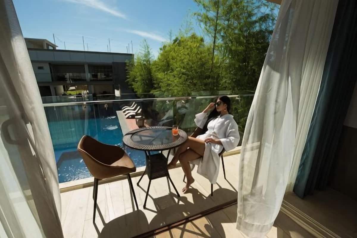 A balcony with a glass railing, a pool, and a table with chairs.