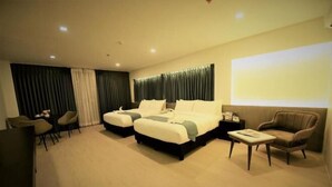 A hotel room with two beds, a desk, a chair, and a sofa. - The First Islatel (Alaminos)