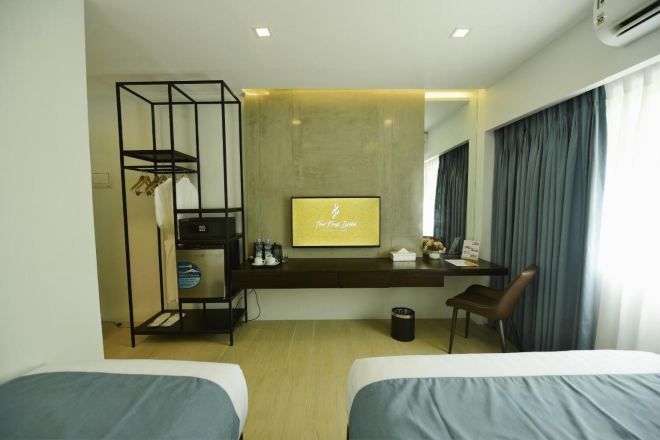 A hotel room with two beds, a desk, a TV, and a wardrobe.