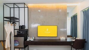 A hotel room with a desk, a TV, a wardrobe, a microwave, and a trash bin. - The First Islatel (Alaminos)