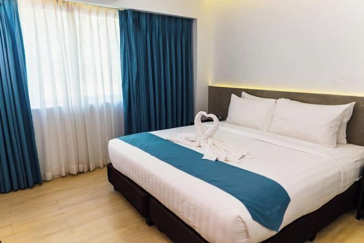 A hotel room with a bed, curtains, and a headboard.