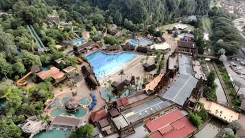 An aerial view of a resort with multiple swimming pools, a large central pool, and various recreational areas surrounded by lush greenery.