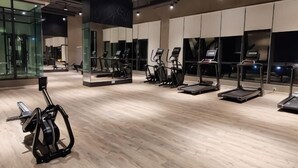 Un gimnasio con equipamiento de ejercicio, ventanas amplias y suelo de madera.
