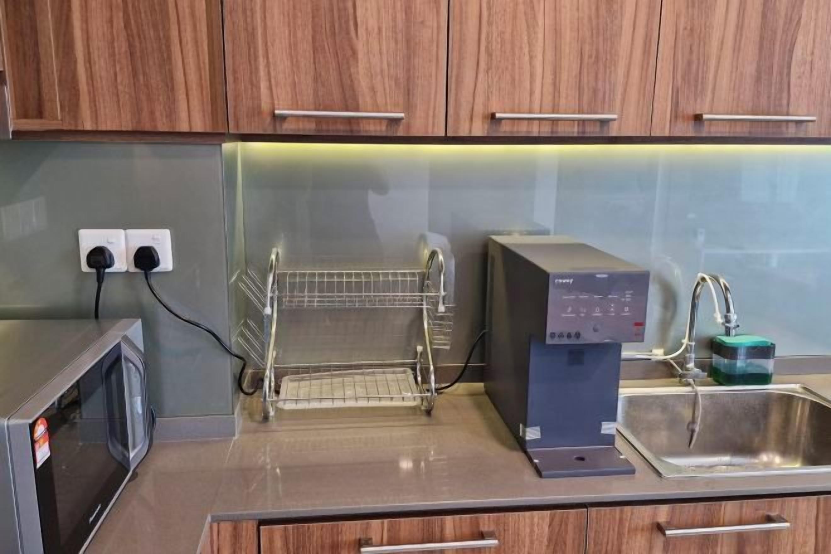 A kitchen with a microwave, a water dispenser, and a sink.