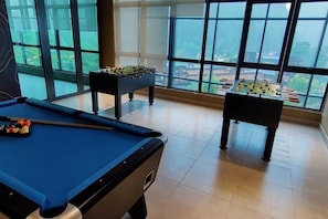 A pool table with a foosball table and a billiards table in a room with large windows. - H&W Sunway Onsen Suite S-13-05 near Lost World of Tambun Ipoh (Ulu Kinta)