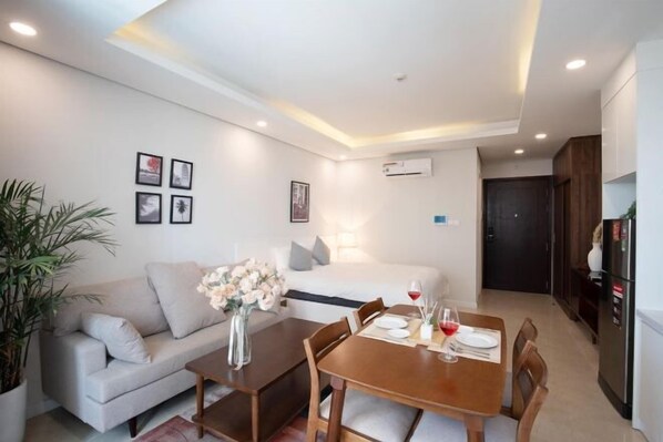 Une chambre d’hôtel moderne comprenant un coin repas, un canapé, une table dressée pour deux personnes et un lit.
