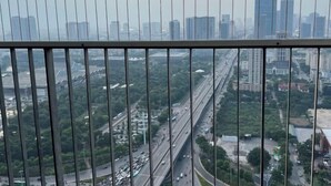 Een hoog gebouw met uitzicht op een stadsbeeld, inclusief een snelweg en meerdere wolkenkrabbers.