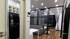 Een moderne kamer met een grijze bank, een witte tafel en een zwarte koelkast.