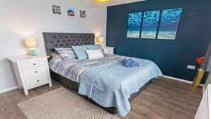 Ein Schlafzimmer mit Bett, Nachttischen, Teppich und Bildern an der Wand.