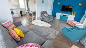 Ein modernes Wohnzimmer mit einer Couch, Sesseln, einem Couchtisch und einem Fernseher.