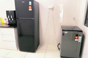 Una cocina con un refrigerador negro, un refrigerador pequeño gris y una cafetera.