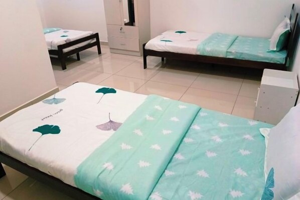 Una cama individual con colcha estampada de hojas, una mesita de noche y un velador.