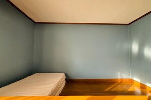 A room with a single bed, a wooden floor, and light blue walls. - 2-floor house with garden (Otaru)