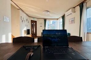 A laptop on a table in a room with a wooden floor, a door, and a window. - 2-floor house with garden (Otaru)