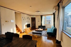 A living room with a sofa, coffee table, and a TV. There is a staircase leading to another room. - 2-floor house with garden (Otaru)