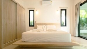 A modern bedroom with a large bed, built-in wardrobe, and a view of greenery through the window. - Samui Paradise Poolside Villa (Koh Samui)