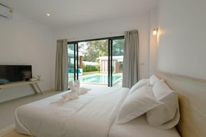 A hotel room with a large bed, a flat-screen TV, and a view of a swimming pool.