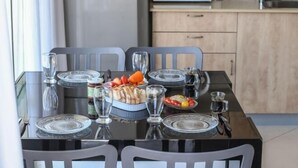 A dining table set with plates, glasses, and food in a modern kitchen with cabinets and a microwave. - Elegant Sea-View Apt w Mamad by Sea N' Rent (Tel Aviv)