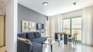 A modern living room with a sofa, coffee table, and dining area. - Elegant Sea-View Apt w Mamad by Sea N' Rent (Tel Aviv)