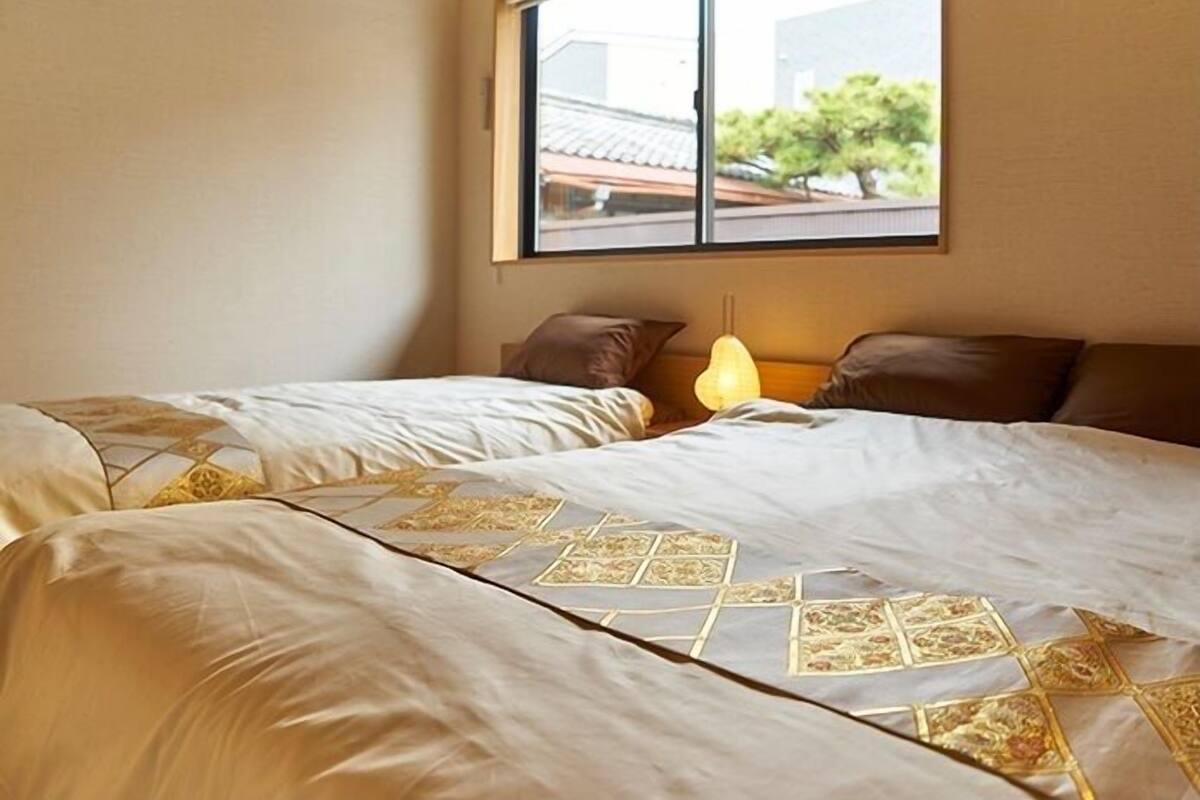 A bedroom with two beds, a window, and a wall-mounted air conditioner.