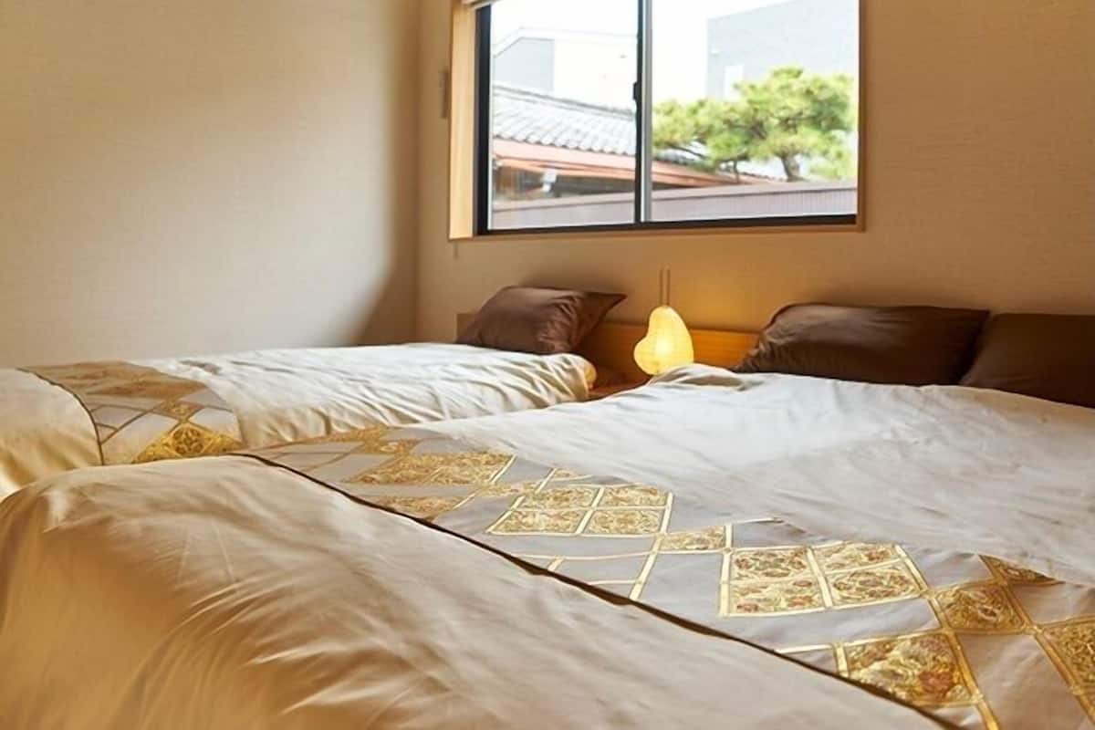 Un dormitorio con dos camas, una ventana y aire acondicionado instalado en la pared.