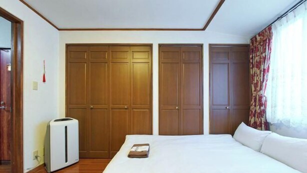A bedroom with a bed, a heater, and wooden wardrobes. - House TOKYO ASAKUSA (Tokyo)