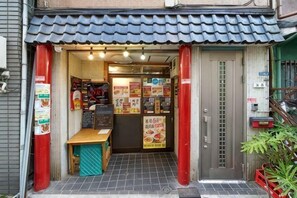 A small restaurant entrance with a tiled roof, a wooden table, and various posters on the walls. - House TOKYO ASAKUSA (Tokyo)