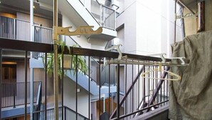 A balcony with a metal railing, a clothes drying rack, and a potted plant. - House TOKYO ASAKUSA (Tokyo)
