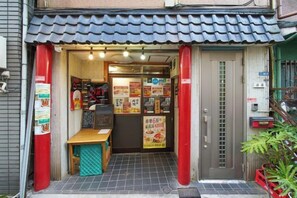 A restaurant entrance with a tiled roof, a wooden bench, and a door with a glass panel. - House TOKYO ASAKUSA (Tokyo)