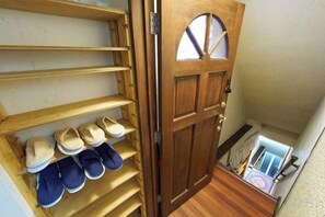 A wooden door with a shoe rack to the left, leading to a staircase. - House TOKYO ASAKUSA (Tokyo)