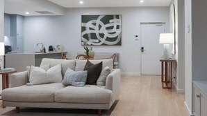 A modern living room with a sofa, a coffee table, and a painting on the wall. - Sea Dunes Luxury Apartment - 10 steps to the beach (Moana)
