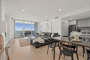 Een moderne woonkamer met een bank, eettafel en stoelen, een keuken en een balkon met uitzicht.