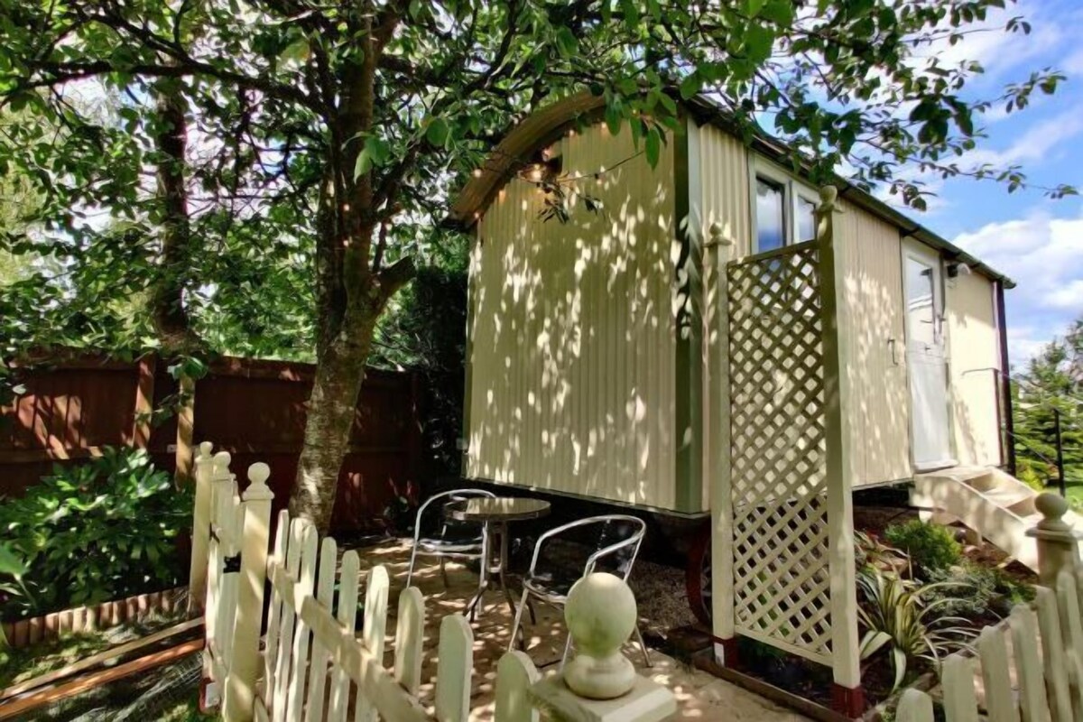 Un petit bâtiment d’un seul étage, à l’extérieur blanc, entouré d’une clôture en bois peinte en blanc. On y trouve deux chaises et une petite table devant l’entrée.