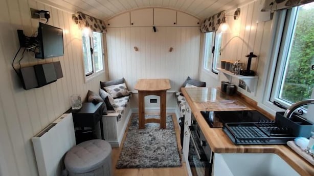 A compact kitchen with a wooden table, a built-in stove, and a window providing a view of greenery.