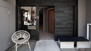 Un ingresso moderno con porta in vetro, una sedia bianca e un piccolo spazio relax all'aperto.