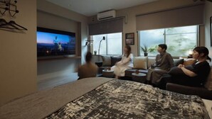 Una moderna camera d'albergo con un ampio letto, una TV a schermo piatto e un'area salotto con divani e tavolino.