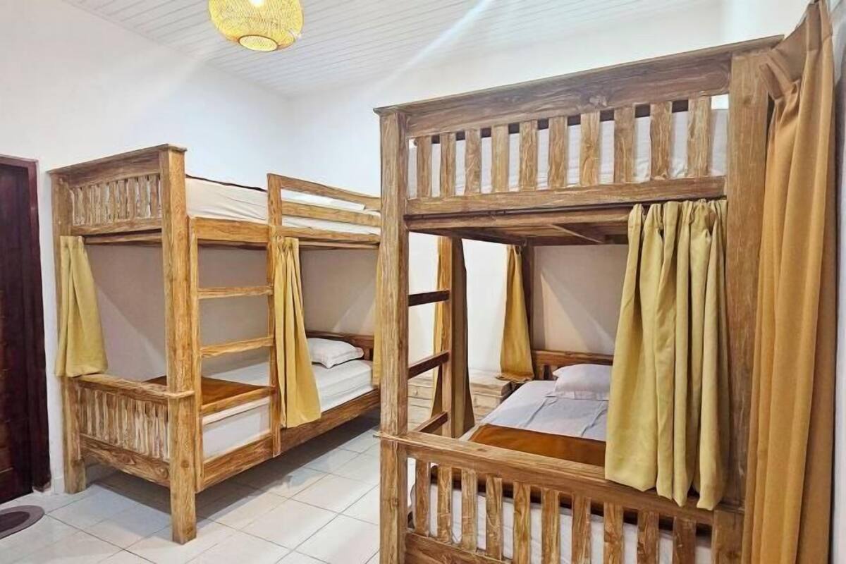 A room with two wooden bunk beds, each with a mattress and a blanket.