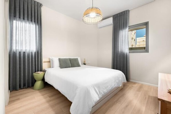 Una camera da letto con un letto, un comodino, una finestra e una lampada a sospensione.