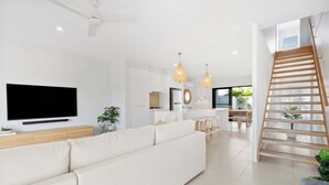 A modern living room with a sofa, a flat-screen TV, and pendant lights. - Seabreeze (kingscliff)