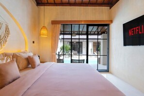 Un dormitorio con una cama grande, una lámpara colgante, vistas al exterior y un cartel de Netflix.