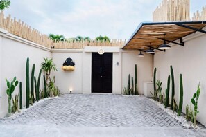A courtyard with a black door, cacti, and a hanging planter. - Villa Terracotta by Pertama Stay (Bali)