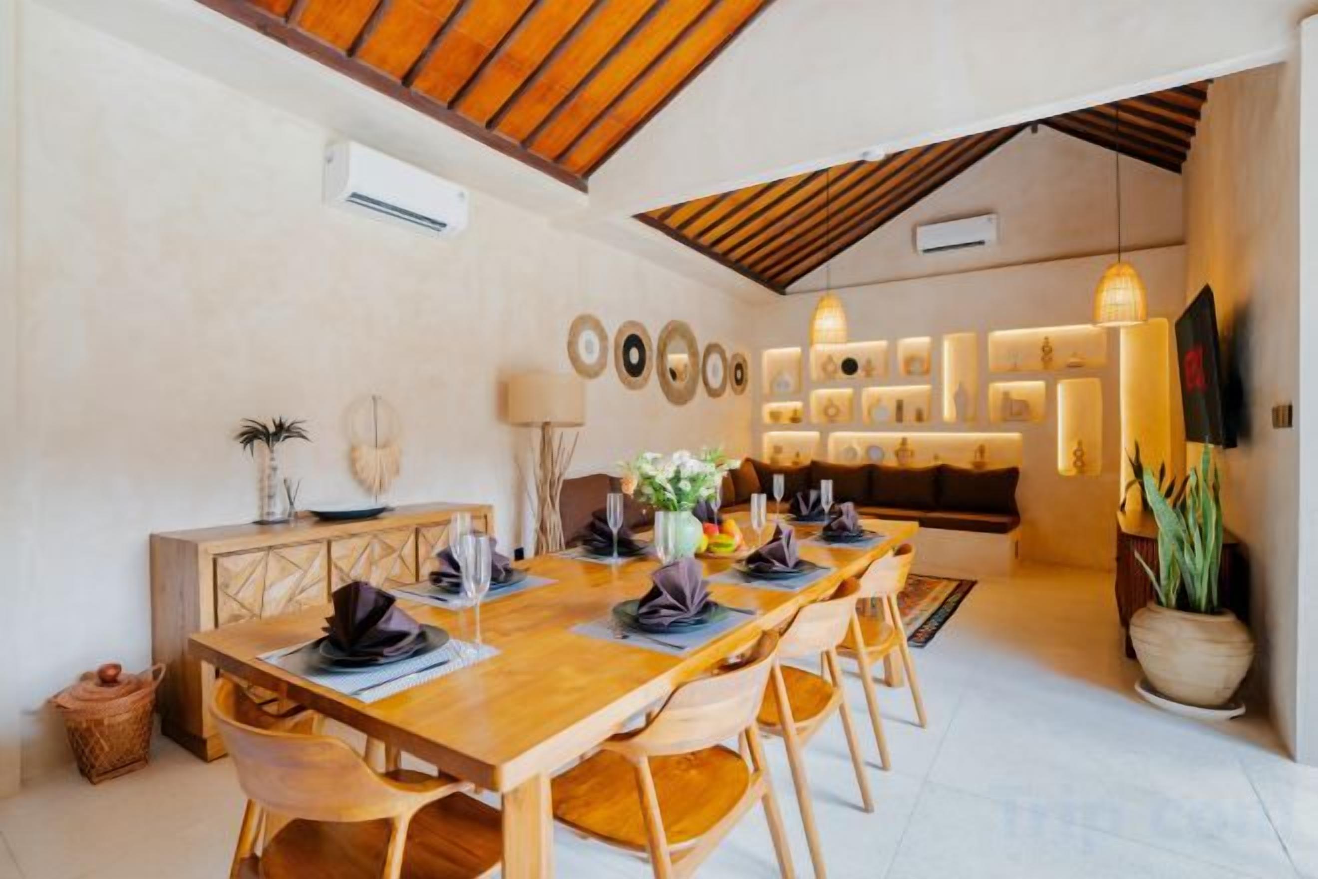 A dining area with a wooden table set for six, surrounded by chairs.