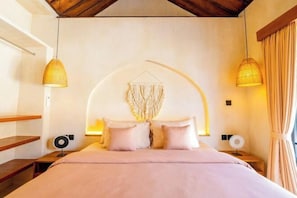 A bedroom with a bed, bedside tables, a wall-mounted light fixture, and a hanging light. - Villa Terracotta by Pertama Stay (Bali)