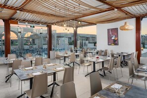 A restaurant with tables set for dining, a view of the cityscape, and a modern ceiling design. - Pickalbatros Luxury Suites (Sharm El Sheikh)