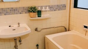 A bathroom with a sink, a bathtub, and a shelf with toiletries. - 5 mins to Motomachi Station/harbour land park B64-1 (Kobe)