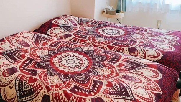 A room with a bed covered in a patterned bedspread, a bedside table with a lamp, and a mirror on the wall. - 5 mins to Motomachi Station/harbour land park B64-1 (Kobe)