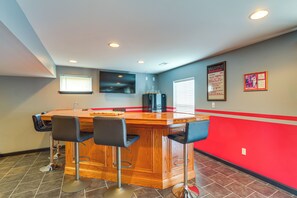 A bar area with a wooden counter and three black bar stools. - Bar, Pool Table & Yard! Spacious Union Home (Union)